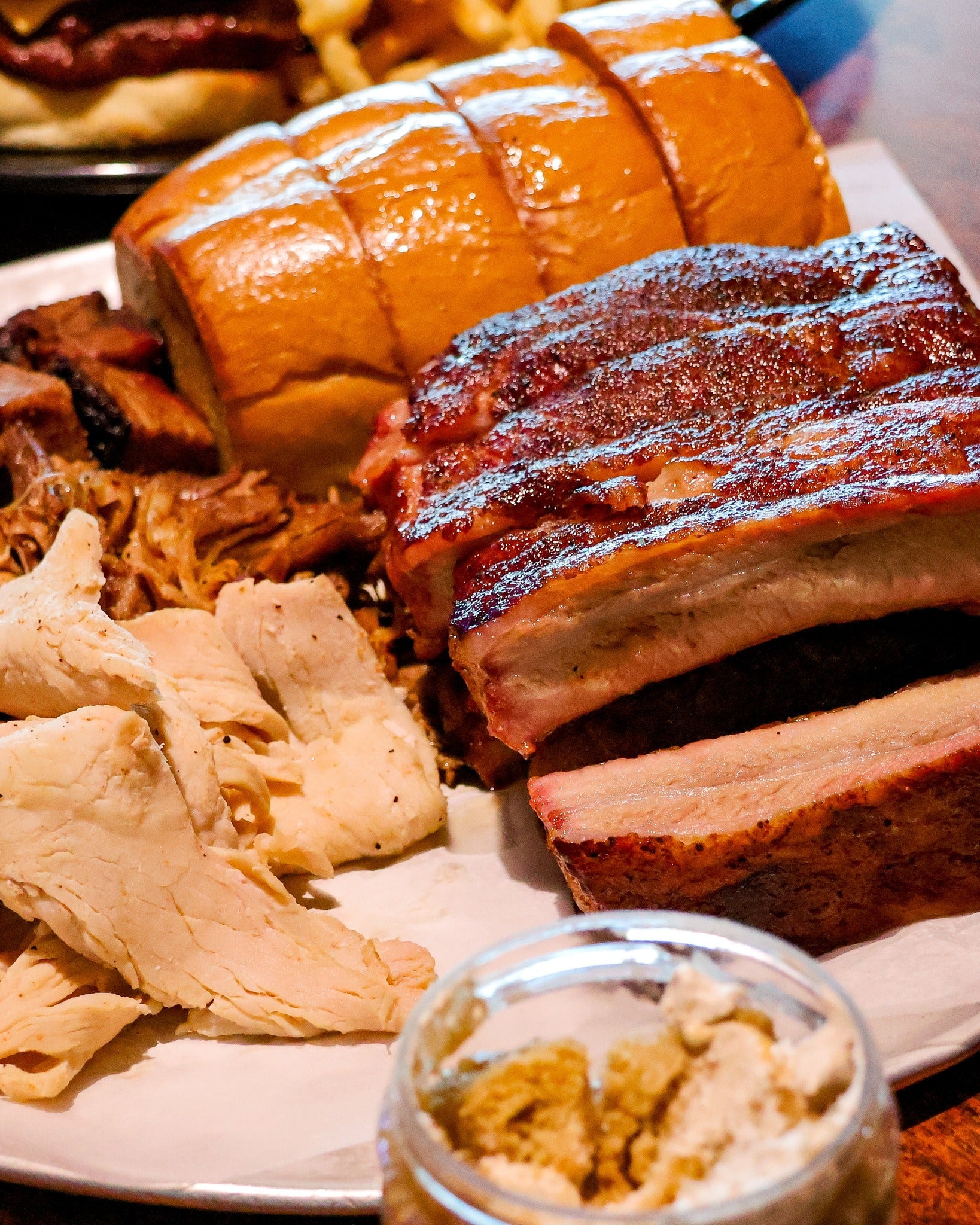 Plate of smoked ribs, pulled pork, sliced turkey, and bread from Smokey D’s showcasing the best BBQ in Iowa.