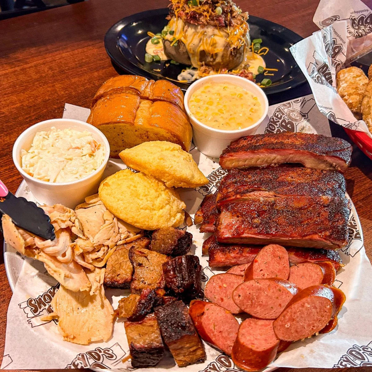 Platter of barbecue meats, sides, and bread on a wooden table