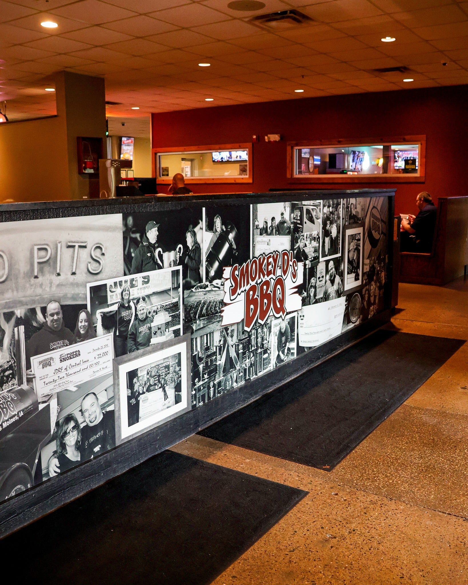 Wall with black and white photos and 'Smokey D's BBQ' sign in a restaurant setting