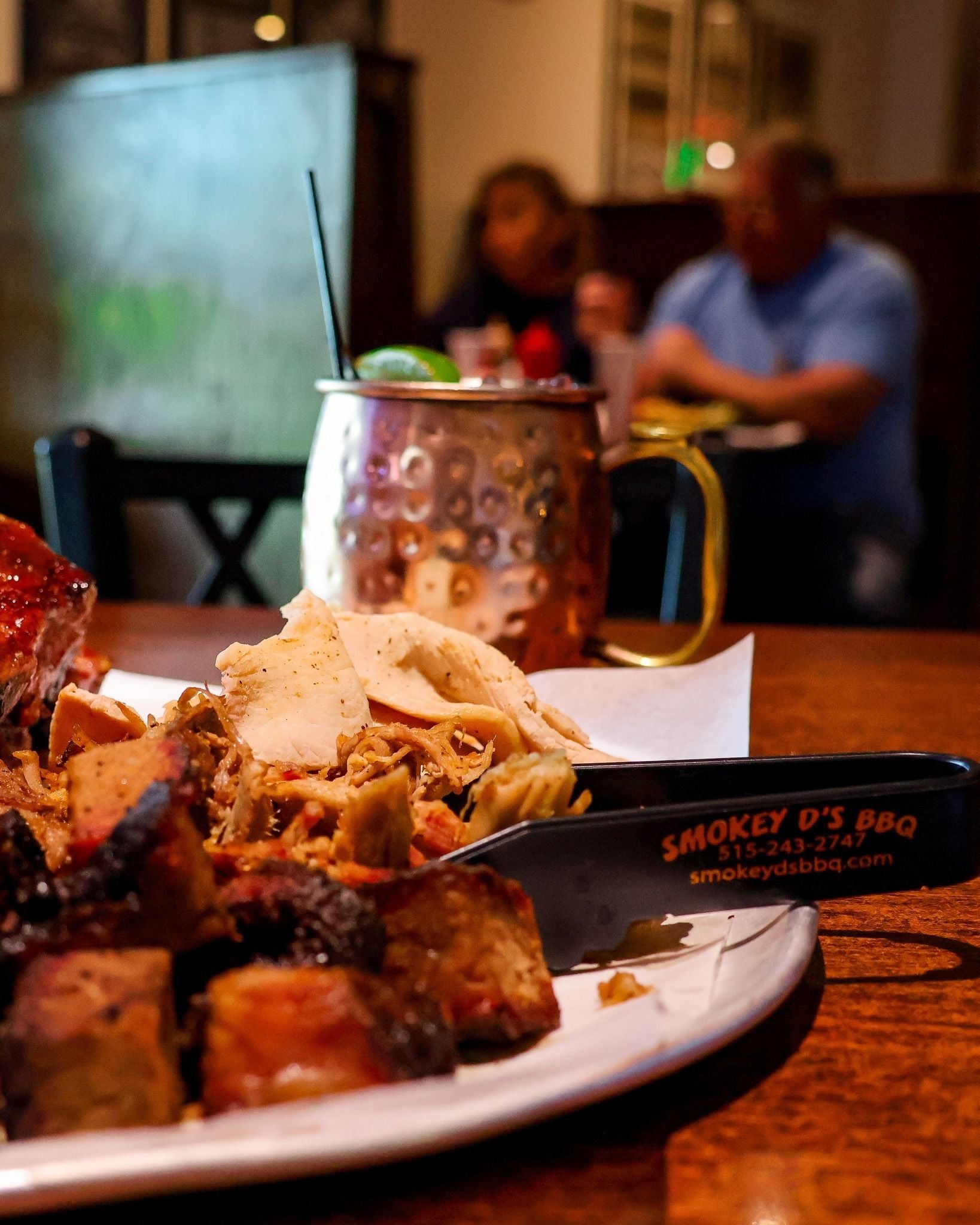 Plate of food with a knife labeled 'Smokey D's BBQ' on a table with a blurred background