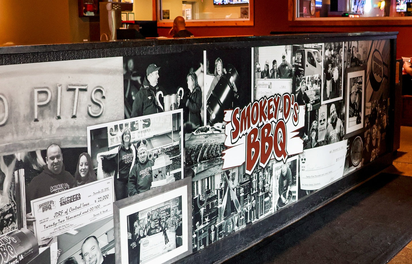 Wall with black and white photos and 'Smokey D's BBQ' sign inside restaurant.